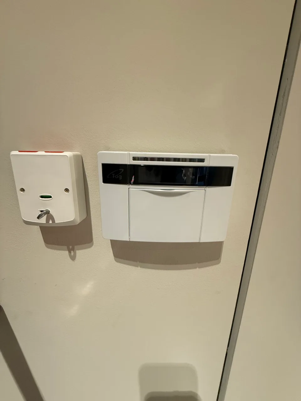 Wall-mounted intruder alarm equipment beside a fused electrical switch, photographed on an EVER-GUARD installation